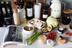 Various colorful healthy food and vegetables locating on countertop next to many different utensils and white kettle during cooking in stylish kitchen